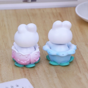 Rear view of cute rabbit figures in blue and pink flower bases on wooden desk
