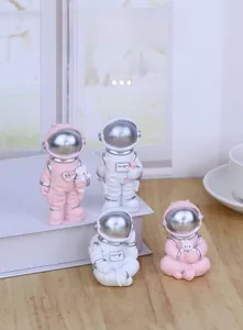 Creative pink and white astronaut figurines with metallic silver visors on a desk