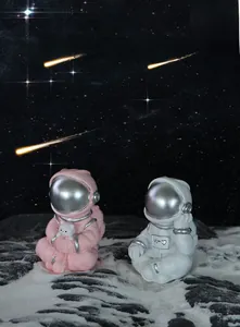Close-up of cute pink and white astronaut figurines with silver visors on lunar surface