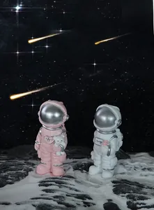 Detail of pink and white astronaut figurines with rose and bear on lunar surface