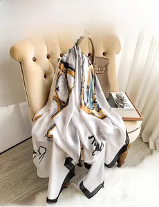 Artistic abstract print silk scarf draped over a classic handbag in a luxury home setting