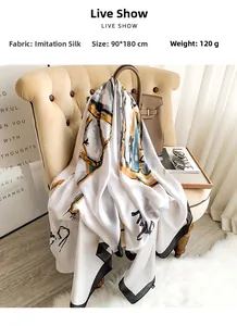 Elegant silk-like scarf draped on a chair featuring abstract gold and grey prints