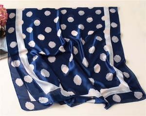 Detailed close-up of dark blue silk scarf featuring elegant pink rose floral patterns