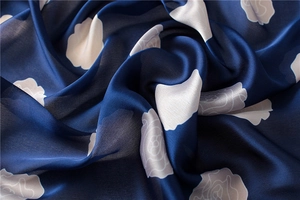 Detailed macro view of navy silk scarf featuring elegant white rose floral patterns