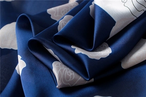 Macro detail of navy blue rose pattern silk scarf with elegant drape and satin finish