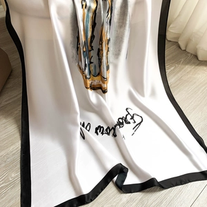 Elegant long silk-feel scarf with black and white floral print on wooden floor
