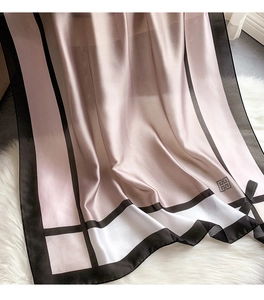 Detail eines Seidenschals mit rosa Farbverlauf, schwarzem Rand und eleganter Schleifendekoration