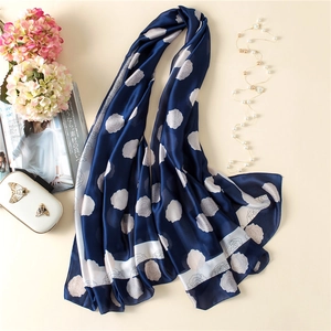 Navy blue silk scarf with white rose print and striped edges on beige background