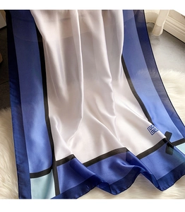 Detail eines Seidenschals mit blauen geometrischen Mustern und Logo-Print im Luxusstil