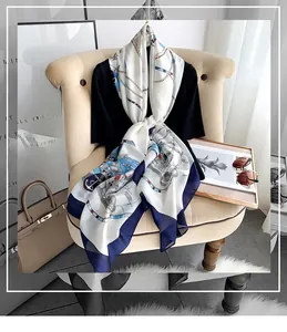 Detail of luxury chain and rope print silk scarf with navy blue border on beige chair