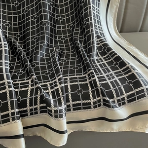 Detailed view of plaid silk scarf with chain patterns and elegant black and white border