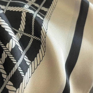 Macro shot of silk-like scarf with black and beige rope pattern and satin texture