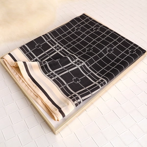 Detailed view of British plaid silk scarf with geometric pattern in golden tray