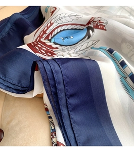 Detail of navy blue and white chain print silk scarf showing soft satin texture and drape