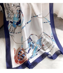 Detail view of nautical print silk scarf with anchors and sailing ships on plush rug
