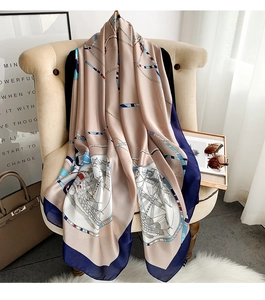 Detail of nautical silk scarf featuring sailboats and anchor chains on a beige chair