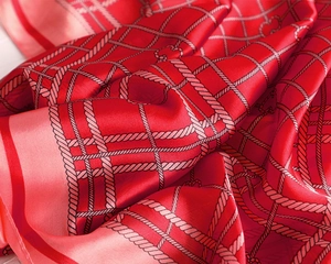Detail of red satin scarf showing intricate rope grid pattern and soft silk texture