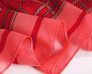 Detail of red plaid scarf showing fine rolled edges and silky polyester texture