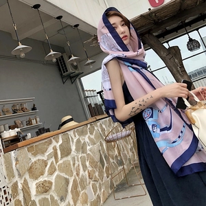Detail of elegant pink and navy silk scarf with chain print styled as a chic headpiece