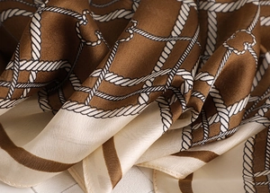 Close-up of silk-like satin scarf featuring brown and beige plaid with white chain pattern