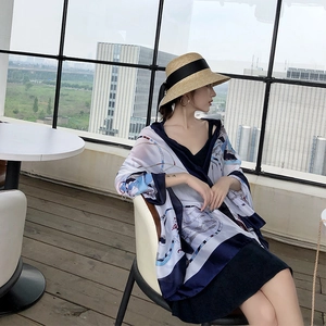 Detail of chain print silk scarf with luxury blue patterns and beach straw hat
