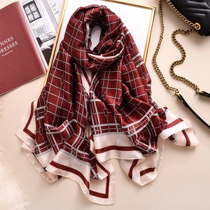 Chic red plaid scarf with bow print and satin finish styled in a luxury setting