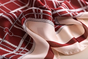 Macro detail of red silk scarf with rope grid pattern showing satin texture and neat stitching