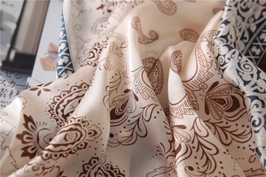 Détail d'un foulard en soie à motif paisley avec fond crème et bordures géométriques