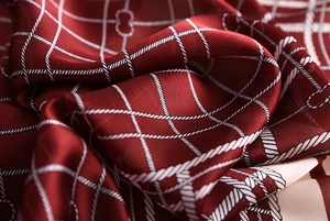 Macro view of burgundy silk scarf showing soft satin texture and white rope grid pattern