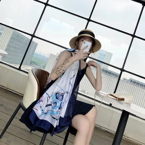 Woman wearing a navy silk-feel scarf with chain print and a white strap dress