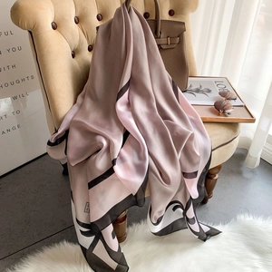 Eleganter Seidenschal mit rosa-grauem geometrischem Schleifenmuster auf dem Sofa