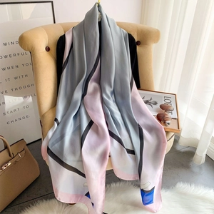 Eleganter Seidenschal für Damen mit geometrischem Muster in Grau und Rosa auf einem Sessel