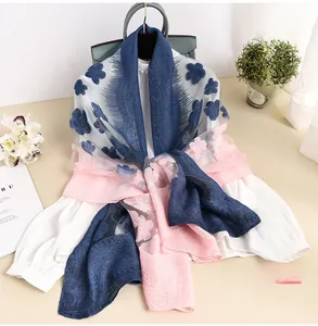 Dettaglio di un'elegante sciarpa in pizzo sfumato blu e rosa con motivi floreali 3D