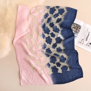 Dettaglio della sciarpa sfumata rosa e blu con ricami floreali 3D e bordi in pizzo