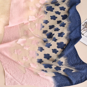 Dettaglio della sciarpa sfumata rosa e blu con applicazioni floreali e pizzo