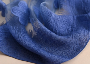 Vista macro del ricamo floreale blu navy su tessuto di pizzo leggero e semitrasparente
