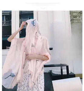 Detail of light pink floral scarf in sheer fabric worn by a model in soft lighting