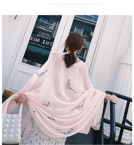 Close-up of pink sheer shawl with bird prints draped over a floral dress and pearl bag