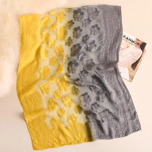 Dettaglio di scialle in pizzo sfumato giallo e grigio con fiori 3D e bordi a conchiglia