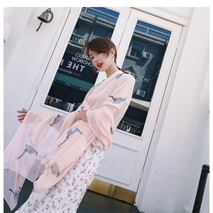 Close-up of pink chiffon shawl with blue floral prints worn by a model in outdoor light