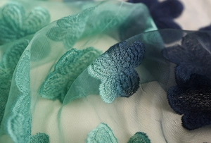 Dettaglio di un foulard in pizzo verde menta con ricamo floreale 3D su tulle semitrasparente