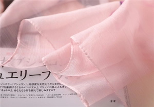 Detail showing the sheer cherry pink silk texture and fine rolled edges of the scarf