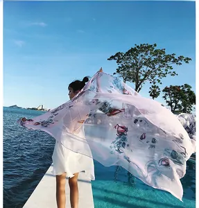 Light pink floral silk scarf flowing in the breeze with ocean resort background