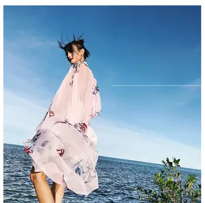 Lightweight pink floral chiffon scarf flowing in the sea breeze with a blue sky background