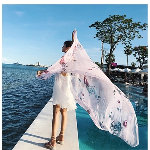 Close-up of lightweight pink floral scarf draped elegantly at a seaside resort setting