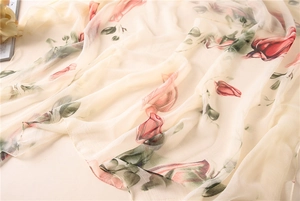 Close-up of elegant cream silk scarf with red rose print and soft texture