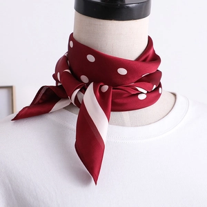 Gros plan d'un foulard en soie bordeaux à pois avec des rayures sur un mannequin