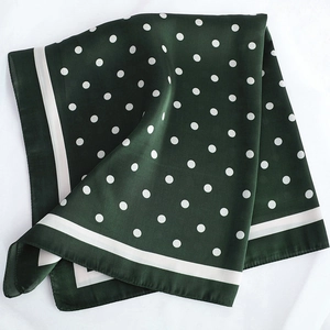 Détail d'un foulard en satin vert foncé à pois blancs et bordure rayée