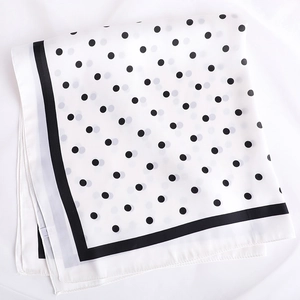 Gros plan d'un foulard en soie léger à pois avec bordure noire décorative sur tissu