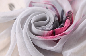 Detailed macro view of pleated silk scarf featuring elegant floral prints and textures